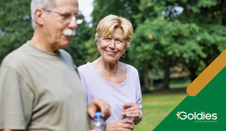 Casal de idosos com garrafas de água mineral nas mãos em um passeio ao ar livre, ilustrando o post "Saiba tudo sobre vida saudável acima dos 60"