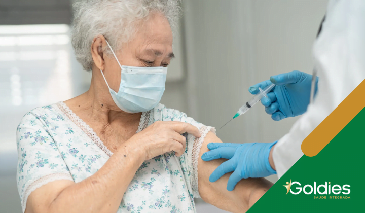 Adulto mais velho recebendo uma injeção de vacina de um profissional de saúde, ilustrando o post "Vacinas que todos os idosos precisam"