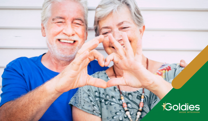 Casal de idosos sorridentes fazendo um formato de coração com as mãos, ilustrando o post "Sexo depois dos 60: Desmistificando o Tema"