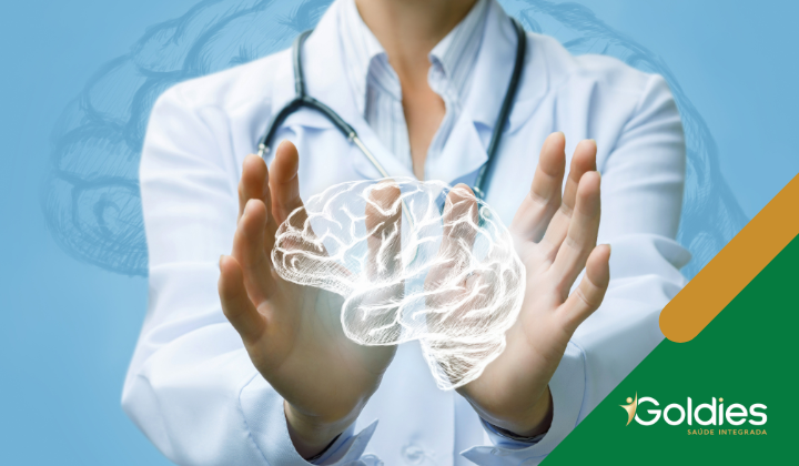 Um médico segurando um holograma cerebral brilhante entre as mãos. A pessoa está usando um jaleco branco e um estetoscópio, em um fundo azul com uma ilustração fraca do cérebro. O logotipo da Goldies Saúde Integrada está no canto inferior direito.