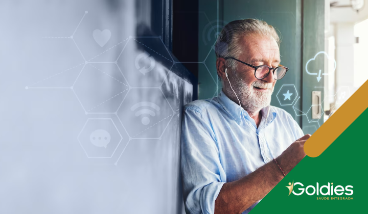 Homem idoso com óculos e fones de ouvido encostado na parede, olhando para um smartphone. Ele está sorrindo levemente. O fundo apresenta ícones de tecnologia tênues. O canto inferior direito mostra um logotipo com o texto Goldies Saúde Integrada.