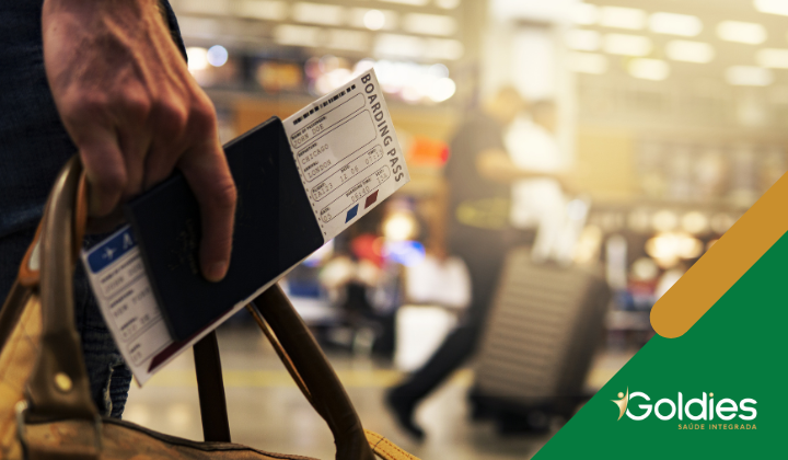 Close na mão de um viajante que segura uma passagem em um terminal de viagens, ilustrando o post "Dicas para viajar com segurança na Terceira Idade"